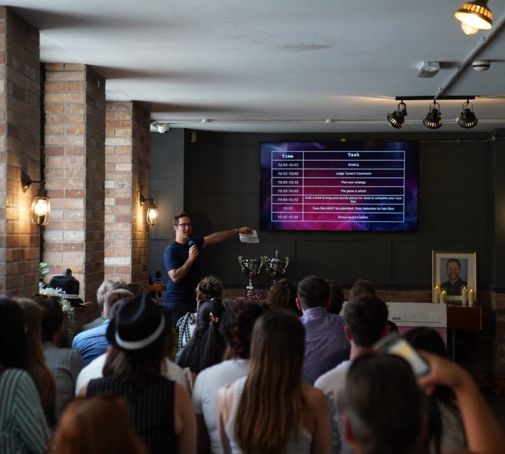 Tom Greveson, Vepple CEO, stands in front of the large crowd delivering a briefing presentation on the TV.