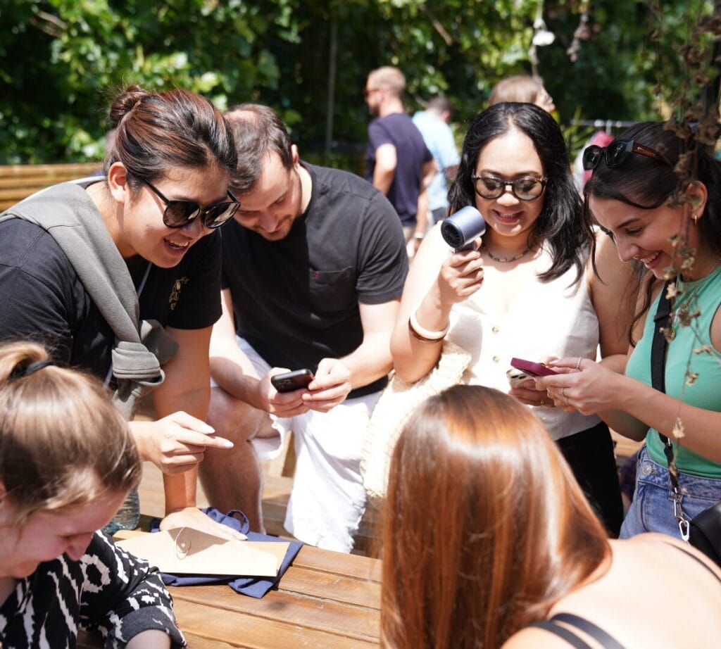 Teams cluster outside to build their game plans. Checking their mobile phones for maps and their answer packs for information.